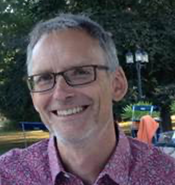 A formal head and shoulder photo of trustee Philip Newton smiling into the camera