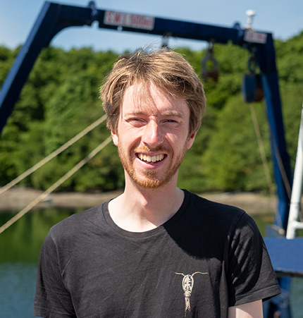 Jamie Rodgers wearing a black T-Shirt standing in front of a SAMS boat