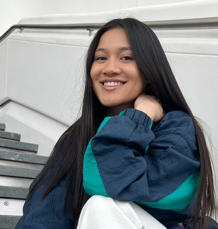 Isabella Cruz, smiling, sitting on the stairs