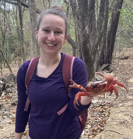 Picture of Charlotte Wilson holding a red crab in a Christmas Island forest