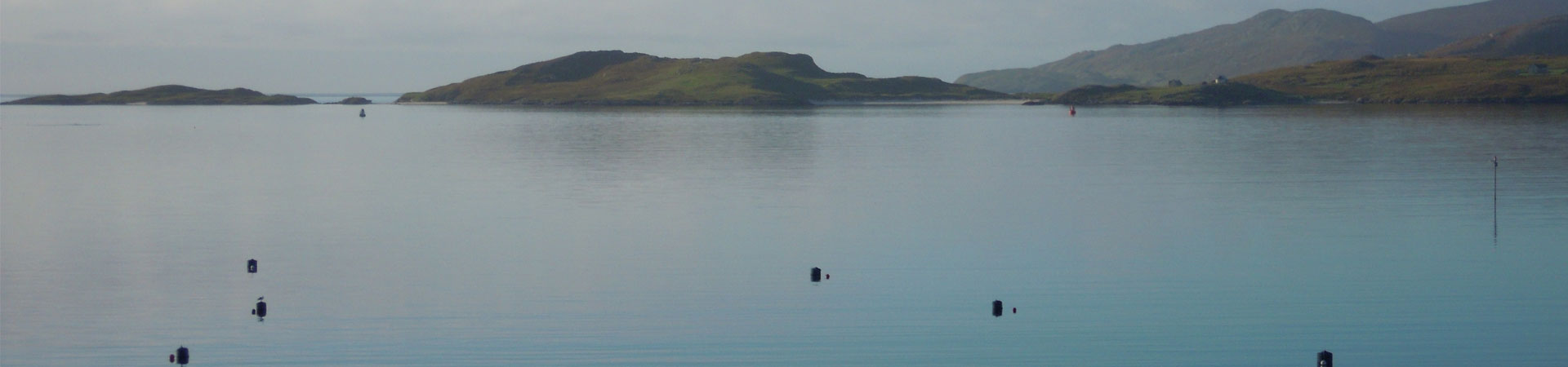 Photo of the sea with some land in the background on the west coast of Scotland with moorings in the foreground
