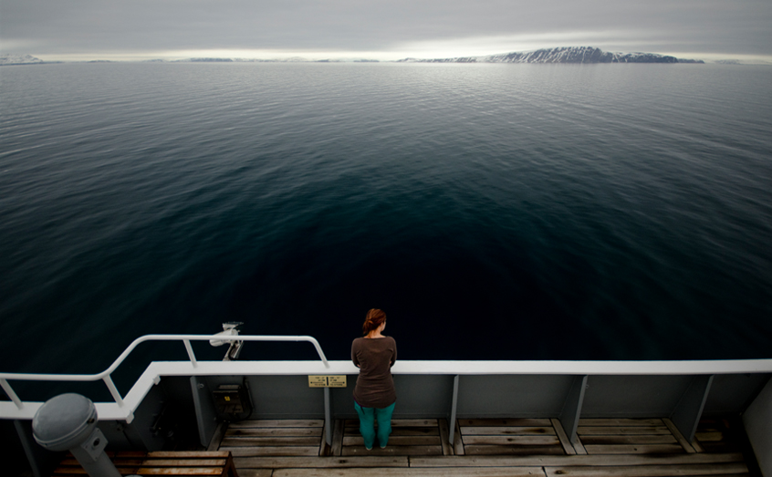 A SAMS scientist scans the Arctic landscape during an ocean research cruise